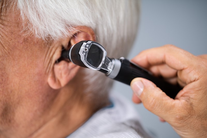 An elderly man gets his ears checked to help improve her hearing health.